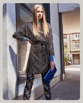 Ana Alcazar Model wears a sequin dress in gold-copper with colorful retro print leggings