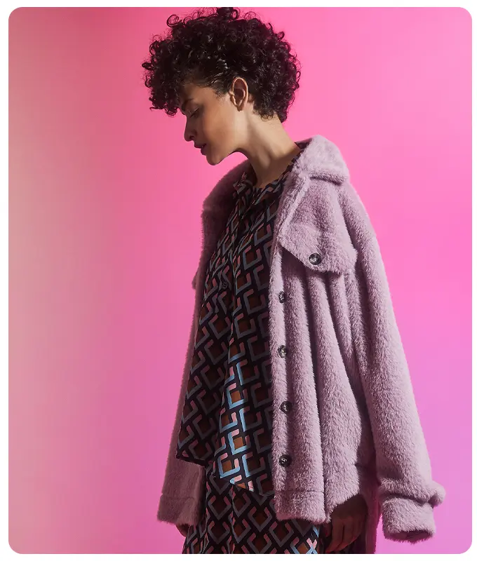 Ana Alcazar Model wears a faux fur jacket in pink combined with a retro print dress